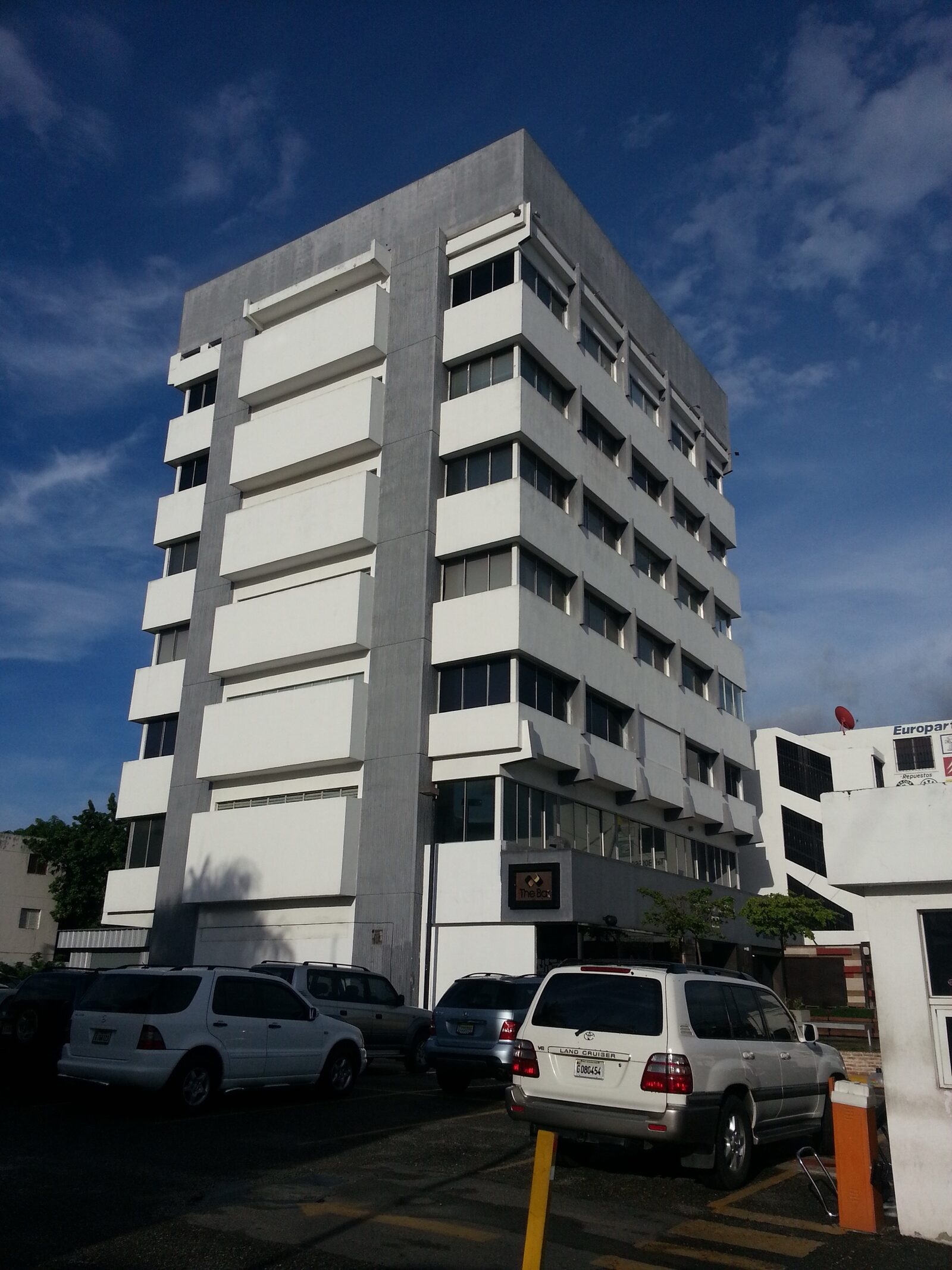 Fachada principal original del edificio W69 antes de la renovación, en concreto blanco con ventanería estrecha.