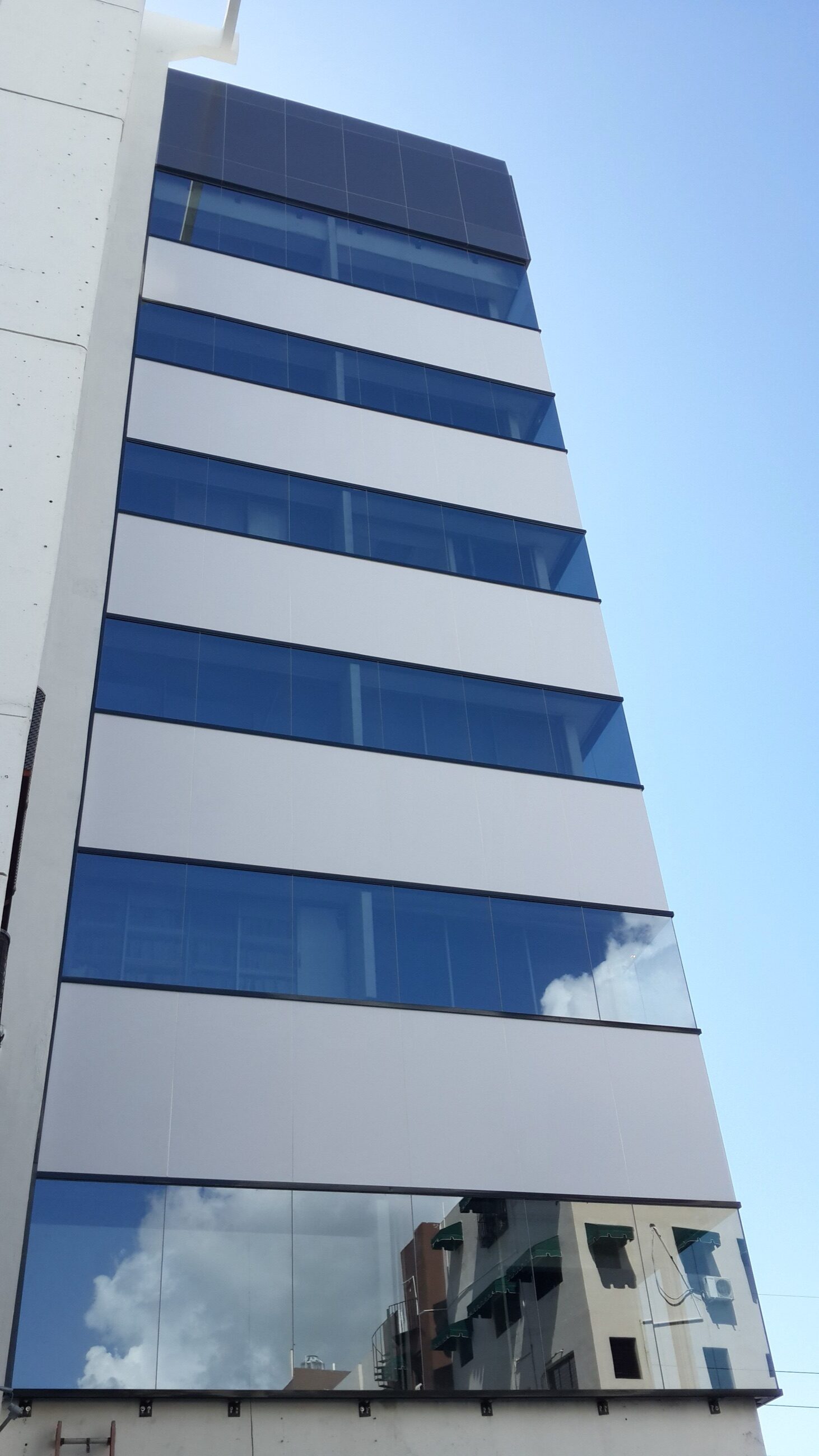 Fotografía de detalle del muro cortina de vidrio instalado en la esquina del edificio W69 durante la obra.